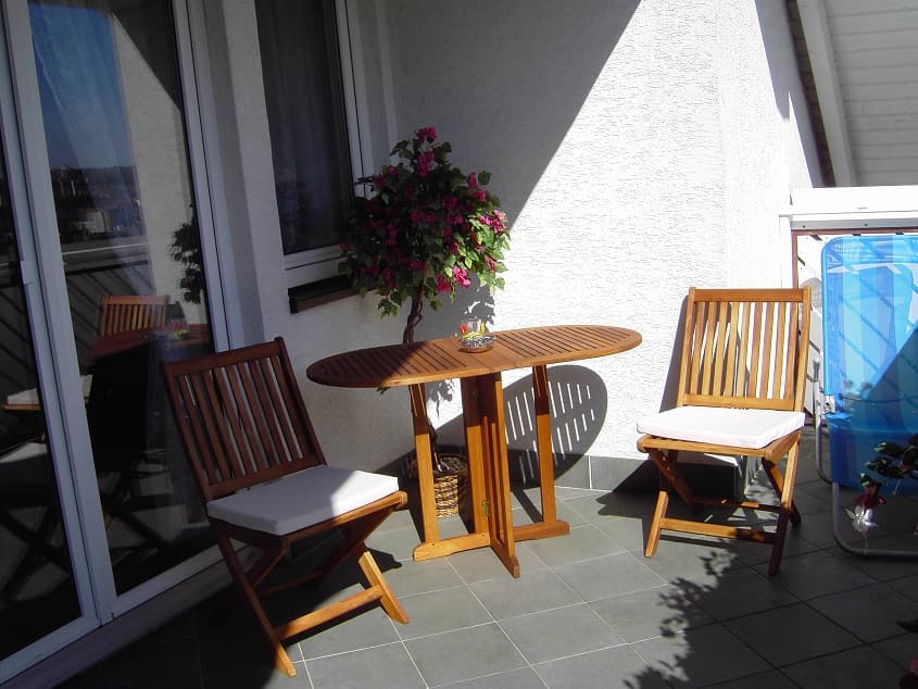 Sonniger Balkon mit Sitzgruppe und Blick in die Landschaft